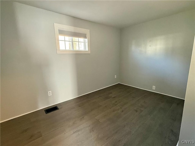 empty room featuring dark wood-type flooring and visible vents