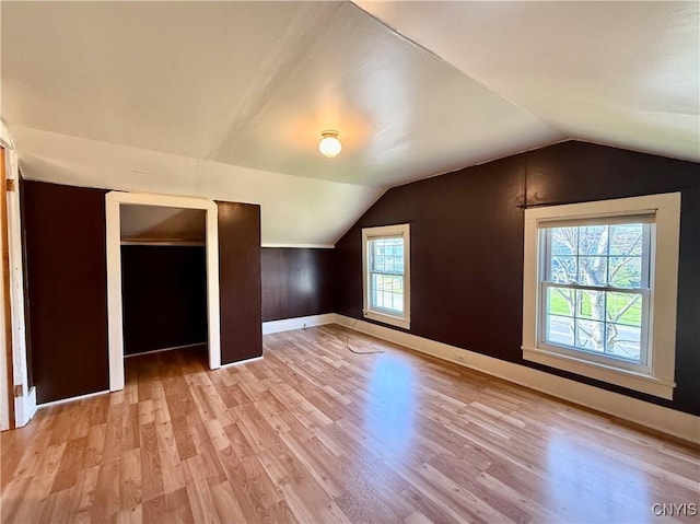 bonus room featuring light wood-type flooring, baseboards, and vaulted ceiling