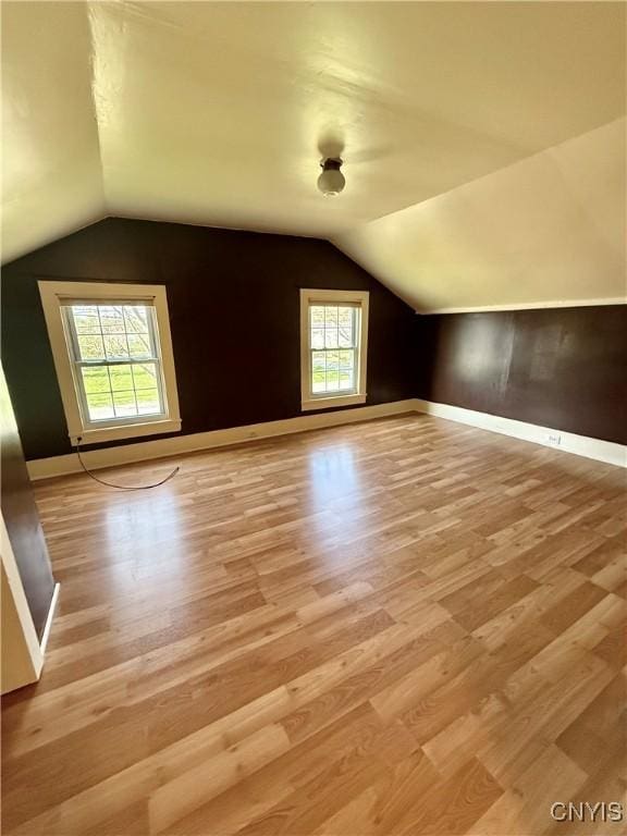 bonus room with plenty of natural light, light wood-style flooring, and lofted ceiling