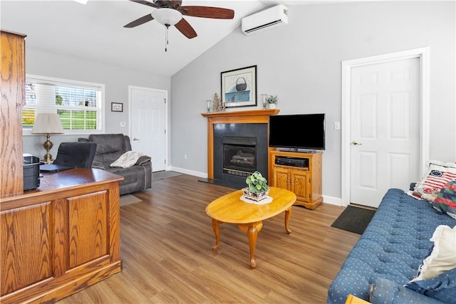 living room featuring wood finished floors, a ceiling fan, a glass covered fireplace, and a wall unit AC