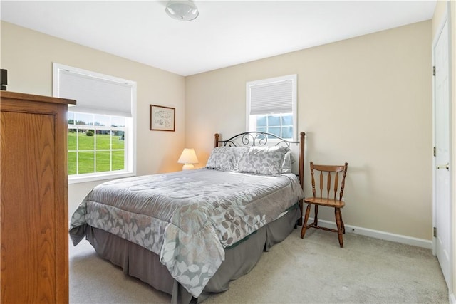 carpeted bedroom featuring baseboards and multiple windows