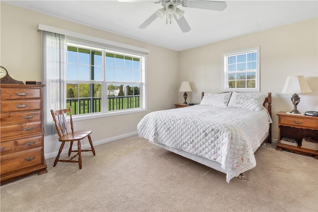 bedroom featuring baseboards, multiple windows, ceiling fan, and light carpet