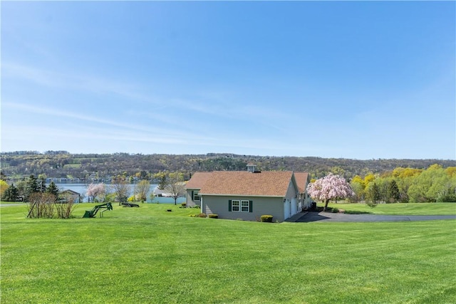 exterior space with an attached garage, a water view, aphalt driveway, and a yard