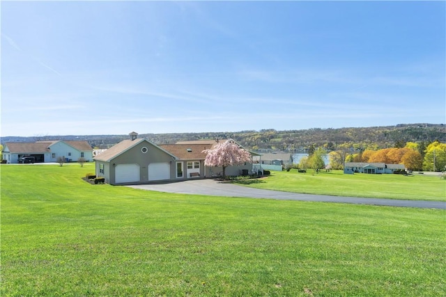 exterior space with an attached garage, aphalt driveway, and a front lawn