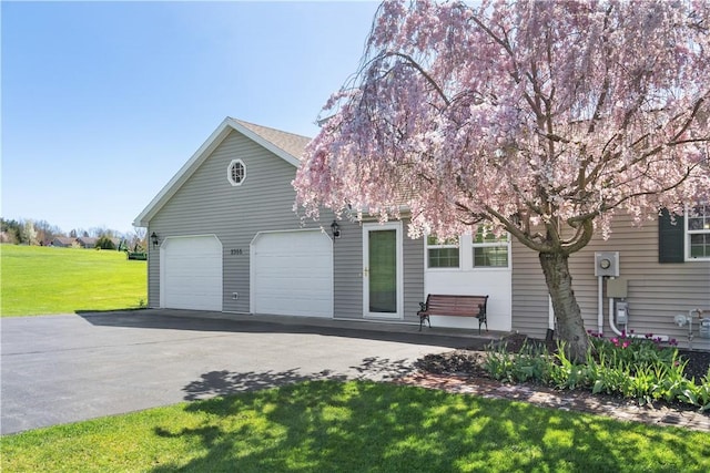 view of front facade featuring a garage, a front lawn, and aphalt driveway