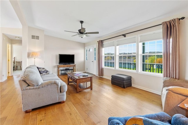 living room featuring ceiling fan, visible vents, light wood-type flooring, baseboards, and lofted ceiling