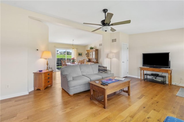 living room with baseboards, visible vents, ceiling fan with notable chandelier, and light wood-style floors