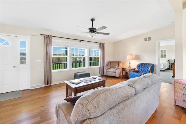 living room featuring a ceiling fan, light wood-type flooring, and visible vents