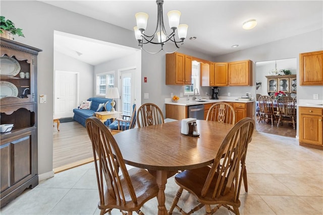 dining space featuring an inviting chandelier, light tile patterned floors, and vaulted ceiling