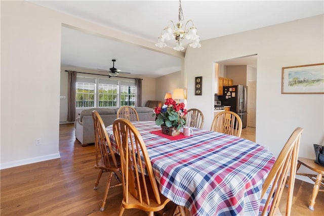 dining room with baseboards, light wood finished floors, and ceiling fan with notable chandelier