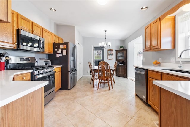 kitchen featuring an inviting chandelier, a sink, light countertops, stainless steel appliances, and light tile patterned floors