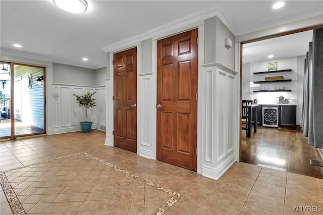 interior space featuring ornamental molding, wine cooler, a decorative wall, recessed lighting, and light tile patterned floors