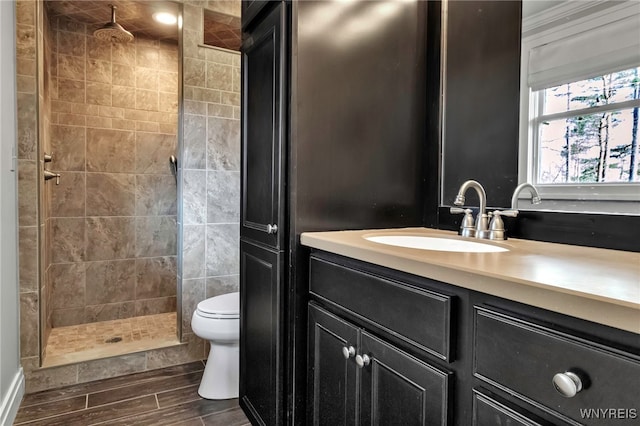 bathroom featuring vanity, wood finish floors, toilet, and tiled shower