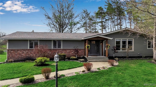 single story home with brick siding, a front lawn, and roof with shingles