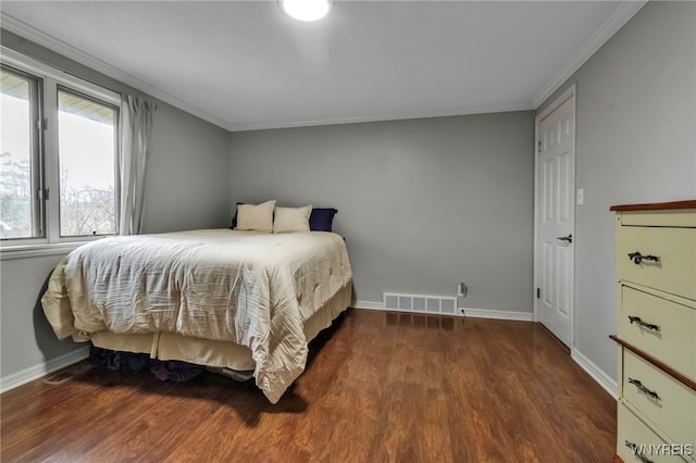bedroom with visible vents, ornamental molding, baseboards, and wood finished floors