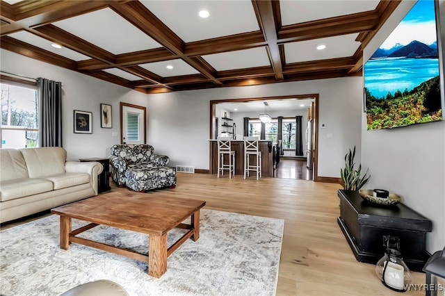 living area featuring visible vents, light wood-style flooring, coffered ceiling, and beamed ceiling