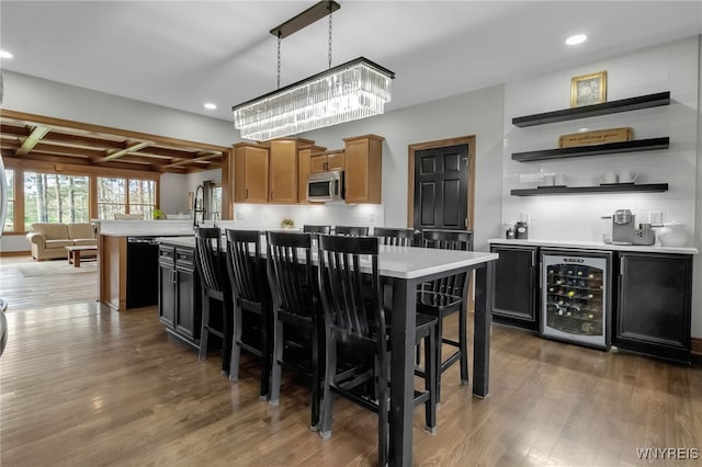 kitchen with light countertops, beverage cooler, stainless steel microwave, and wood finished floors