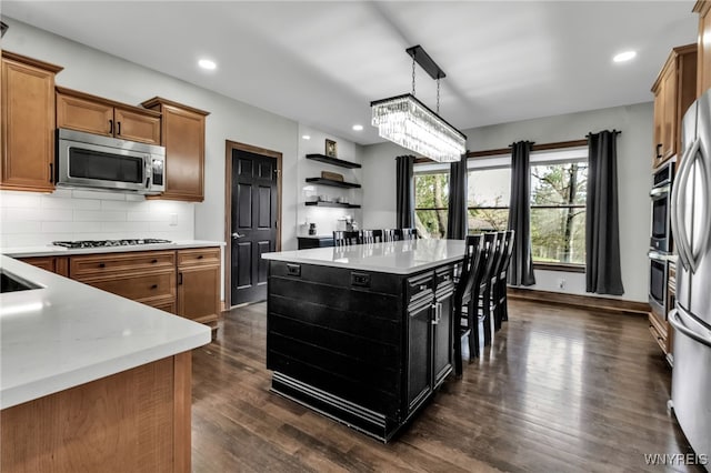 kitchen featuring brown cabinetry, open shelves, stainless steel microwave, and light countertops