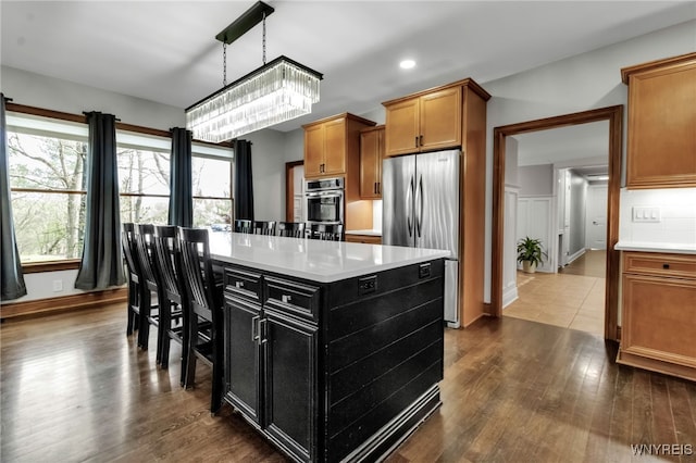kitchen with dark wood-style floors, a center island, light countertops, dark cabinets, and appliances with stainless steel finishes
