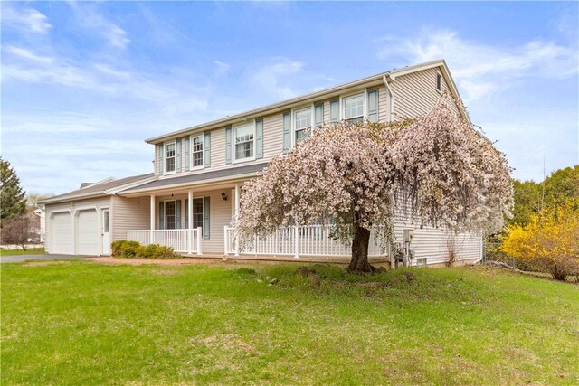 view of front of home with covered porch, an attached garage, driveway, and a front yard