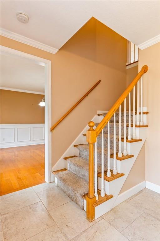 stairs with crown molding and tile patterned flooring
