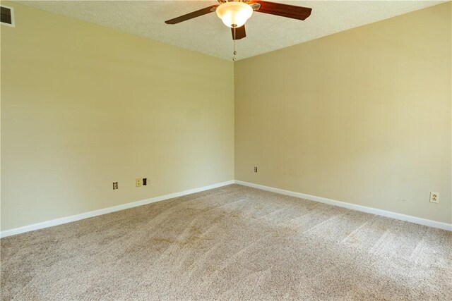 spare room with light colored carpet, baseboards, ceiling fan, and visible vents