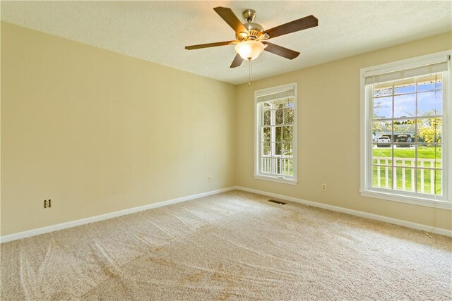 spare room featuring baseboards, a ceiling fan, carpet, and visible vents
