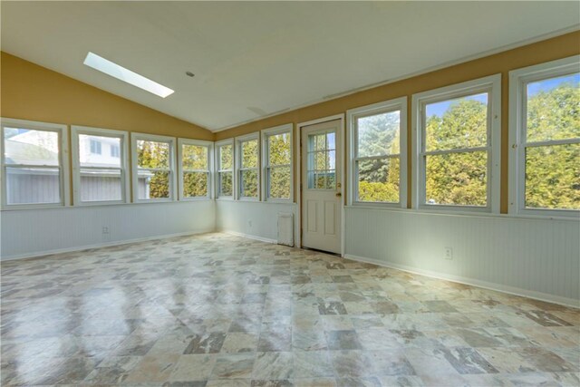 unfurnished sunroom with stone finish floor, plenty of natural light, baseboards, and lofted ceiling with skylight