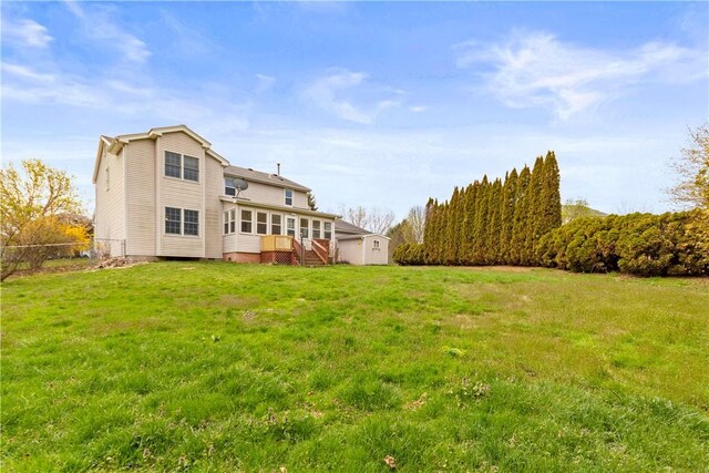 rear view of property featuring a lawn and fence