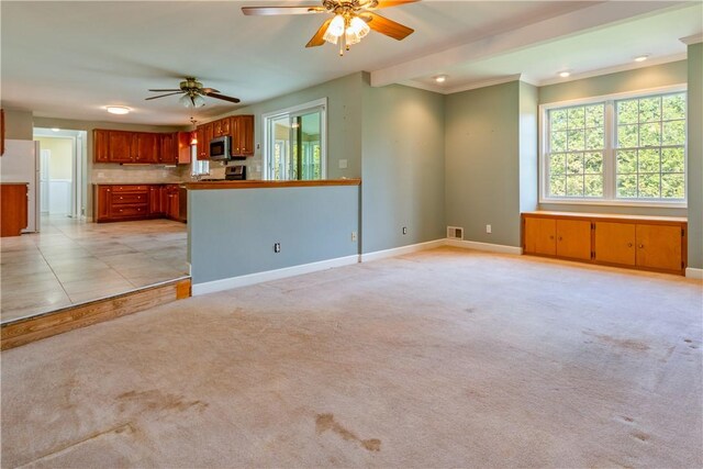 unfurnished living room with ceiling fan, plenty of natural light, and baseboards