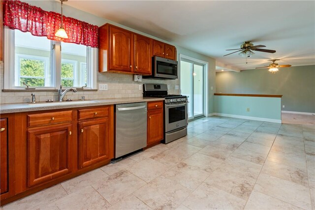 kitchen featuring stainless steel appliances, brown cabinetry, a sink, and tasteful backsplash