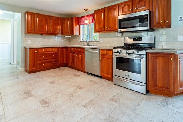 kitchen with light countertops, appliances with stainless steel finishes, decorative backsplash, and brown cabinetry