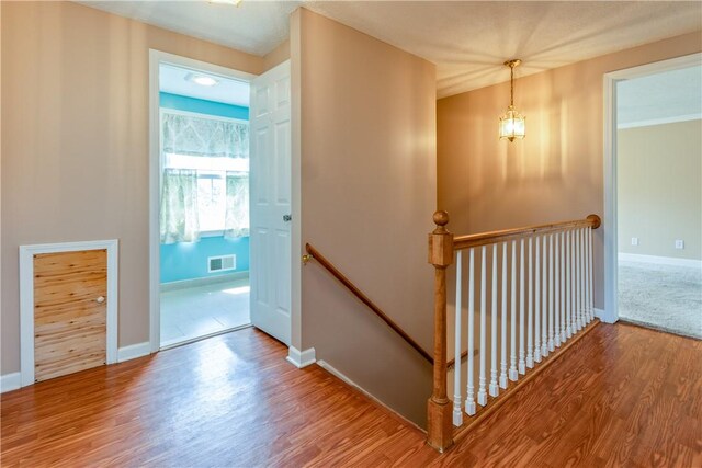 interior space featuring visible vents, baseboards, wood finished floors, and an upstairs landing