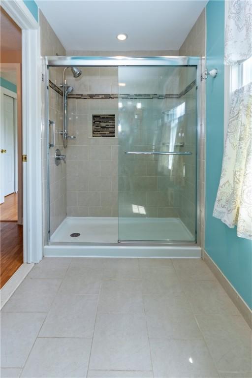 bathroom featuring tile patterned flooring, baseboards, and a stall shower
