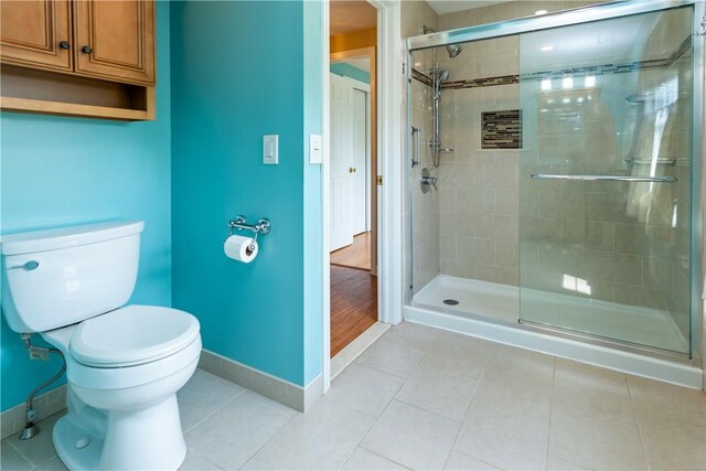 full bath featuring baseboards, tile patterned flooring, a stall shower, and toilet