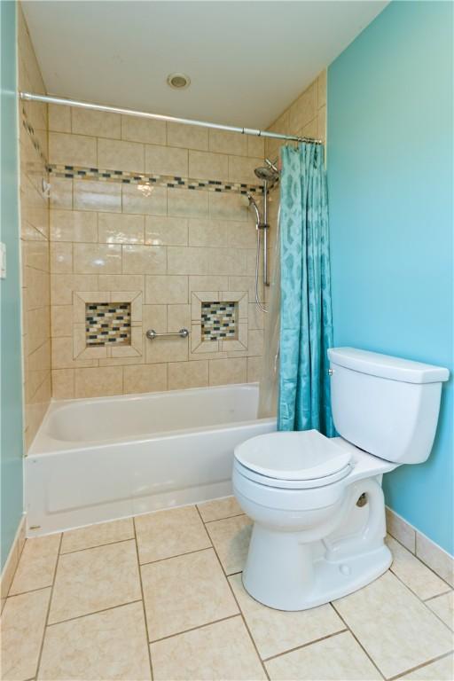 full bath with tile patterned floors, baseboards, shower / bath combo with shower curtain, and toilet