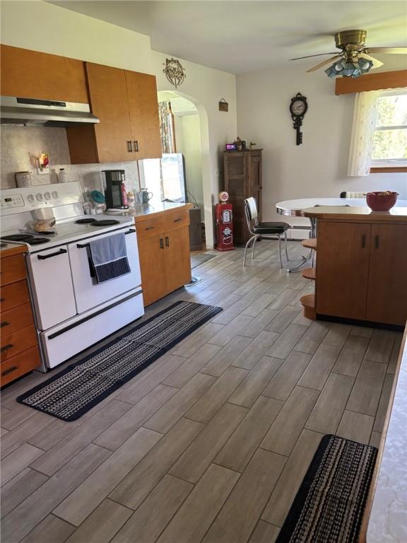 1001 W Broad St, Horseheads, NY 14845 - kitchen with ceiling fan, light wood-style floors, white range with electric cooktop, arched walkways, and under cabinet range hood