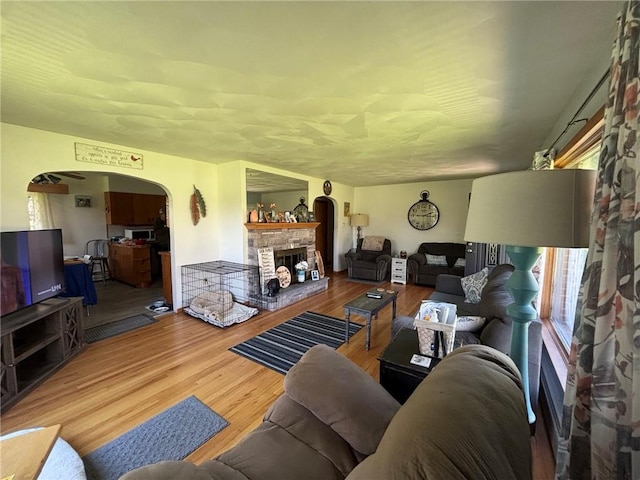 1001 W Broad St, Horseheads, NY 14845 - living room featuring arched walkways, a stone fireplace, and wood finished floors