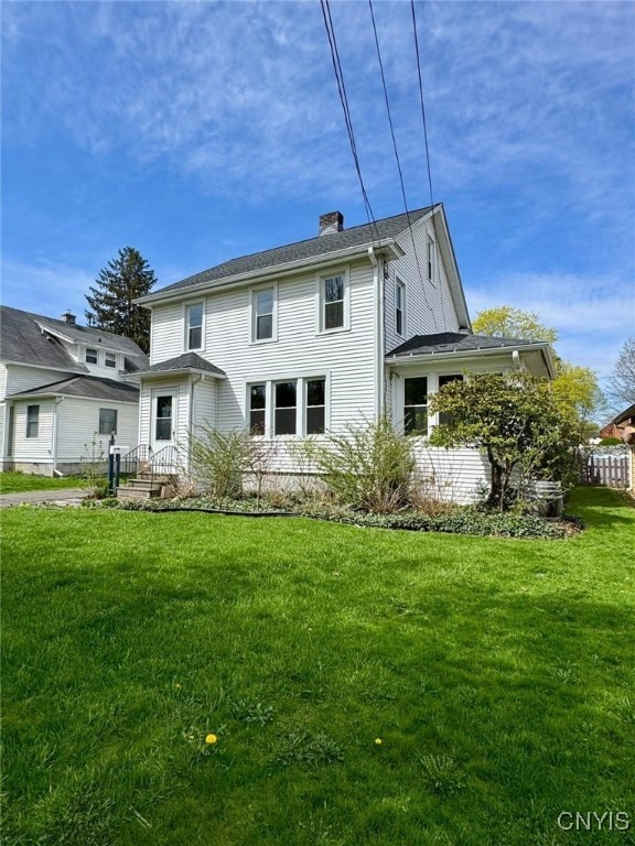 rear view of house featuring a lawn and a chimney