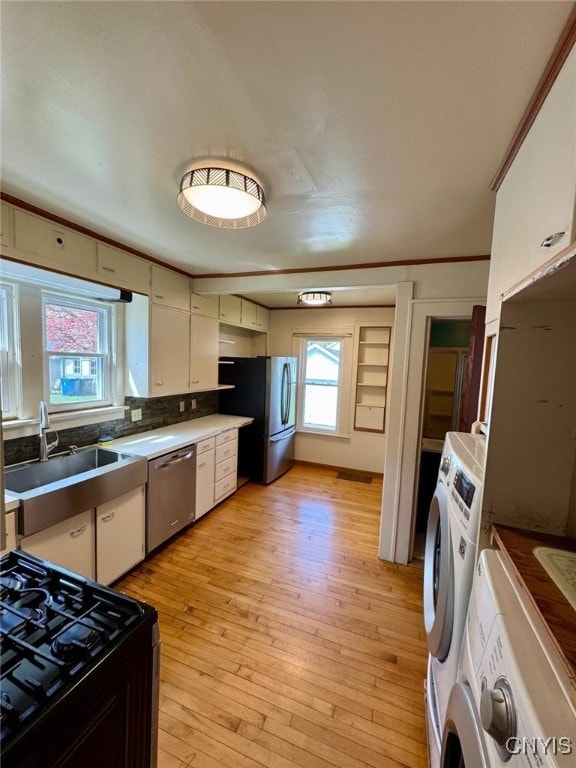 kitchen with washer / clothes dryer, a sink, appliances with stainless steel finishes, and white cabinets