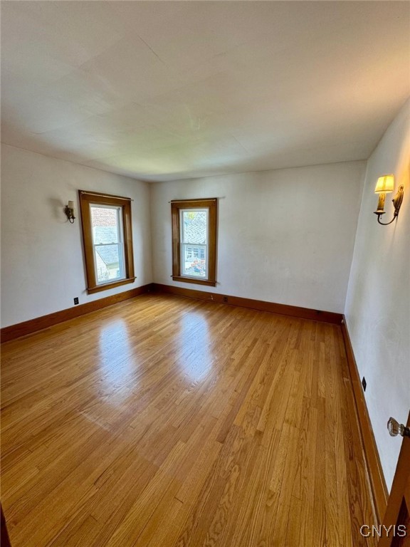 spare room featuring baseboards and light wood-type flooring