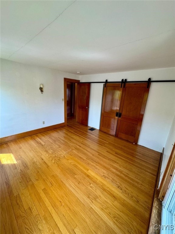 spare room with a barn door, baseboards, and light wood-style flooring