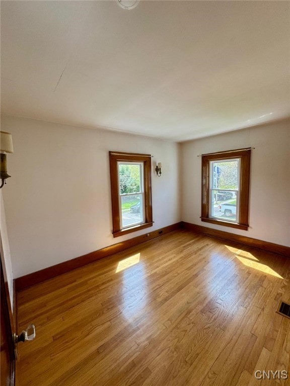 spare room with baseboards, visible vents, and light wood-style flooring