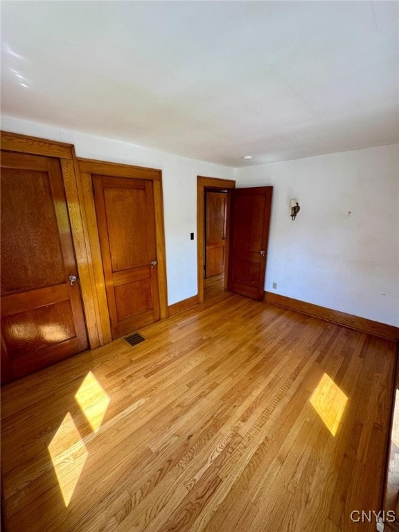 empty room with light wood-style floors, baseboards, and visible vents