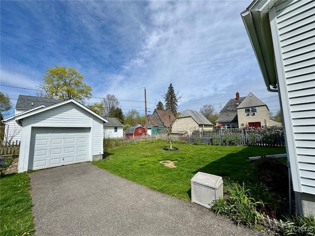 view of yard featuring fence, an outbuilding, driveway, and a detached garage