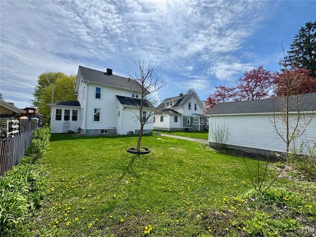 rear view of property featuring a lawn and fence