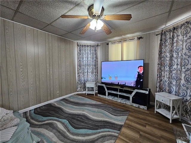 living room with baseboards, ceiling fan, a paneled ceiling, and wood finished floors