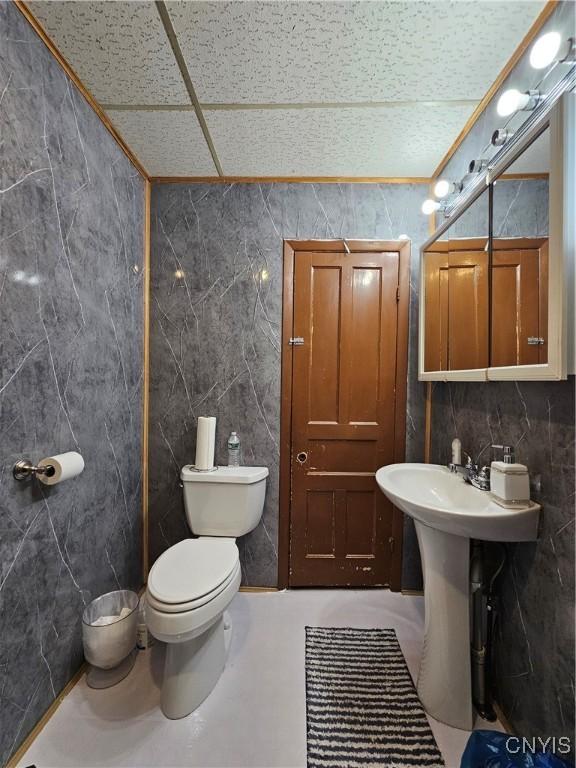 bathroom featuring toilet and tile walls