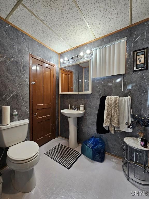 half bath featuring toilet and tile walls