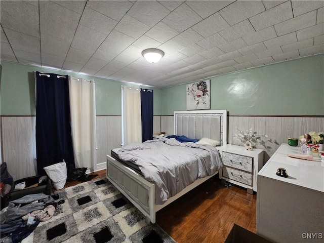 bedroom featuring wainscoting and dark wood-style flooring